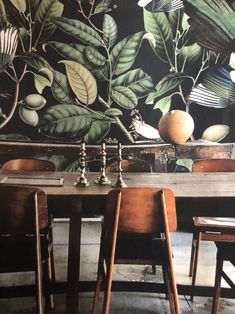 two wooden chairs sitting at a table in front of a mural