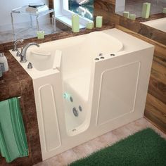 a large white bath tub sitting on top of a bathroom floor next to a green rug