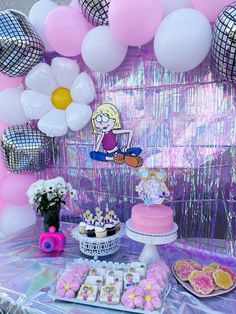 a table topped with cakes and desserts next to pink balloons, flowers and other decorations