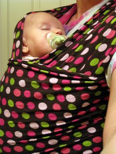 a woman holding a baby in a polka dot wrap