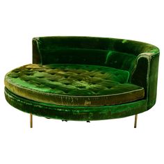 a green round couch sitting on top of a wooden table next to a white wall