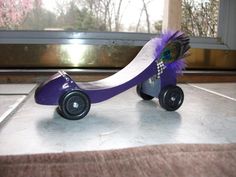 a purple and white toy car with feathers on it's wheels sitting on a counter