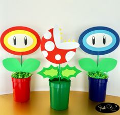 three potted plants sitting on top of a table next to each other with paper cut outs