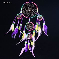 a colorful dream catcher with feathers hanging from it's side on a black background