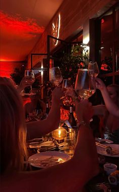 people toasting with wine glasses in a restaurant at night, while the light is on