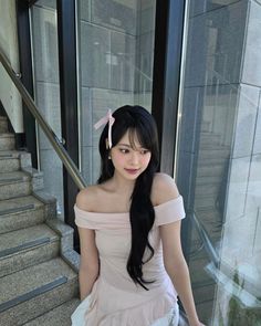 a woman in a dress is sitting on the stairs with her hands behind her back