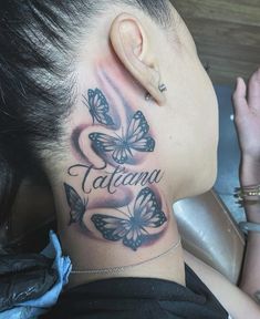 a woman's neck with butterflies on it and the word tattoama written in cursive font