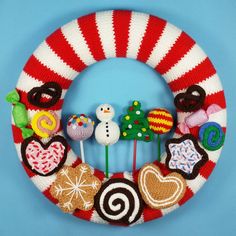 a knitted christmas wreath with candy, candies and snowmen on it against a blue background