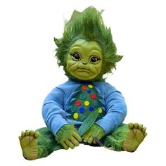 a green troll sitting on the ground with his legs crossed and eyes wide open, wearing a blue shirt