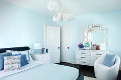 a bedroom with blue walls and white furniture