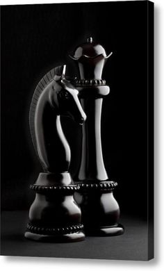 a black and white photo of two chess pieces in the shape of a horse, on a dark background