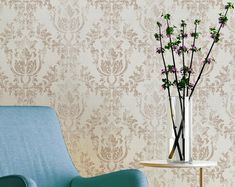 a vase with flowers sitting on a table next to a blue chair and wallpaper