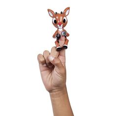 a hand is holding a small toy deer in it's right hand and the other hand is pointing at it