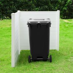 a black trash can sitting next to a white fence