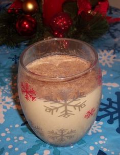 a glass filled with milk sitting on top of a blue table cloth covered in snowflakes