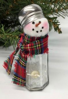 a snowman ornament with a red scarf and plaid scarf around it's neck