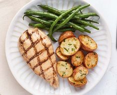 a white plate topped with meat, potatoes and green beans