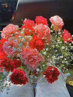 red and white flowers in a vase on the back seat of a car