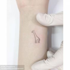 a small giraffe tattoo on the left inner arm and wrist is shown in black ink