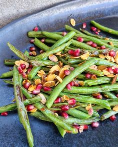 green beans with pomegranate and pistachio seeds on a blue plate