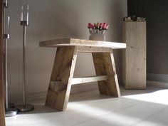 a wooden table sitting in the middle of a room next to a vase with flowers on it