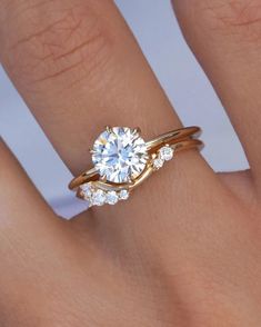 a woman's hand with a diamond ring on top of her finger and an engagement band