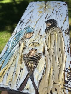 the painting is being displayed on top of a wooden table in front of some grass