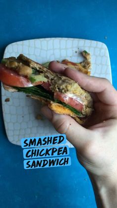 someone is holding up a sandwich on a plate with the words smashed chickpea sandwich