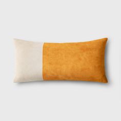 an orange and white pillow on a gray background