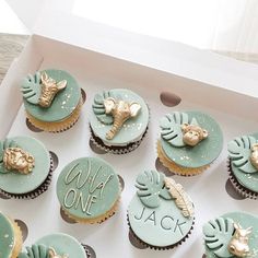 cupcakes decorated with gold and blue frosting in a box