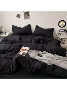 a bed with black sheets and pillows on it