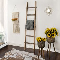 sunflowers are in baskets next to an old ladder and two stools on the floor