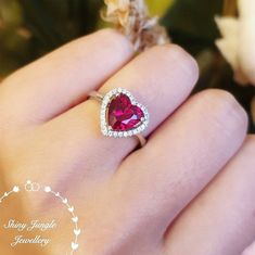 "Hand made 2-carat eq. (8 mm) heart cut lab Ruby engagement ring, with brilliant cut white diamond simulants halo, white gold or rose plated sterling silver, discreetly adjustable band. " Unique on Etsy!  This is a such a romantic ring with a stunning Pigeons blood colour lab Ruby heart shaped centre stone! Great clarity!  Ruby is the most expensive coloured stone every sold in auctions. What matters the most is the colour and transparency as most natural rubies are heavily included, that it is Ruby Heart Ring, July Birthstone Ring, Ruby Heart, Romantic Rings, Ring Ruby, Diamond Heart Ring, Silver Heart Ring, Ruby Engagement Ring, Classic Engagement Rings