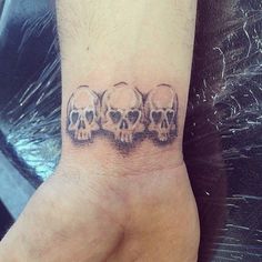 a hand with three skulls on it and one has a small heart in the middle