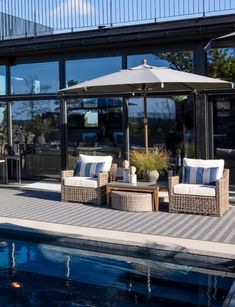 two wicker chairs sitting on top of a wooden deck next to a swimming pool