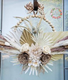 a wreath with flowers and feathers hanging on the front door to decorate it for someone's special occasion