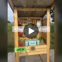 an outdoor stand with vegetables and fruits on it, in the middle of a field