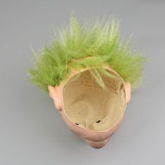 an odd looking vase with green hair on it