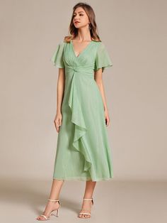 a woman is wearing a green dress with ruffles on the sleeves and shoulders