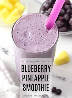 blueberry pineapple smoothie in a tall glass with a pink straw on top