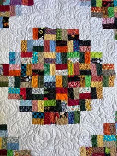 a quilted wall hanging on the side of a white building with lots of different colored blocks