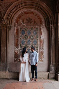 a man and woman standing in front of an archway