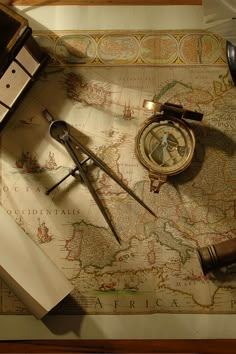 an old world map with compass, tape measure and other items on it next to a pair of scissors