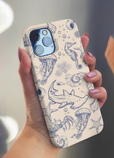 a woman holding up her phone case with an image of fish and sea animals on it