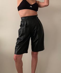 "Amazing retro chic long leather shorts is fully lined with pleats in the front.  Pockets with side zipper and button closure.  Has some spots of wear on the waistband but is overall in good condition. Label Tag: Michael Hoban North Beach Label Size: 3/4 Material: Leather  Best Fits: 23/24 (XXS) Approx. measurements taken laid flat: Waist: 11.5\" (one side) Inseam: Just over 9\" For reference:  Model is 31\" bust, 25\" waist and 34\" hips and normally wears jean size 24 Why do we love vintage? - Short Pleated Bottoms For Night Out, Chic Pleated Leather Bottoms, Retro Black Spring Shorts, Retro Black Bottoms For Night Out, Spring Leather Knee-length Bottoms, Retro Black Bottoms For Work, Retro Black Bottoms For Workwear, Retro Black Workwear Bottoms, Chic Black Knee-length Shorts