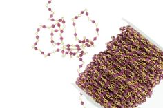 a spool of purple beads next to a chain