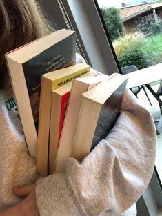 a person holding several books in their hands