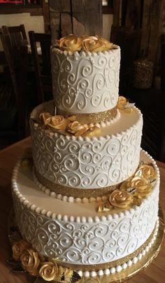 a three tiered white wedding cake with gold flowers