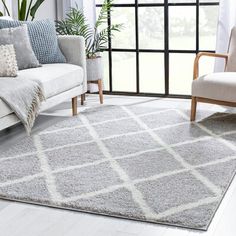 a living room with a couch, chair and rug in front of a large window