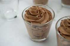 two cups filled with chocolate frosting on top of a table